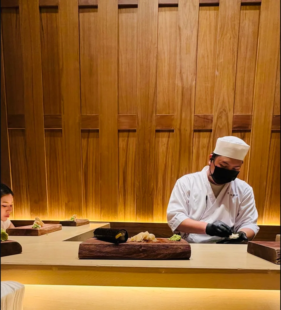A sushi chef working in a warm wood-lined dining room