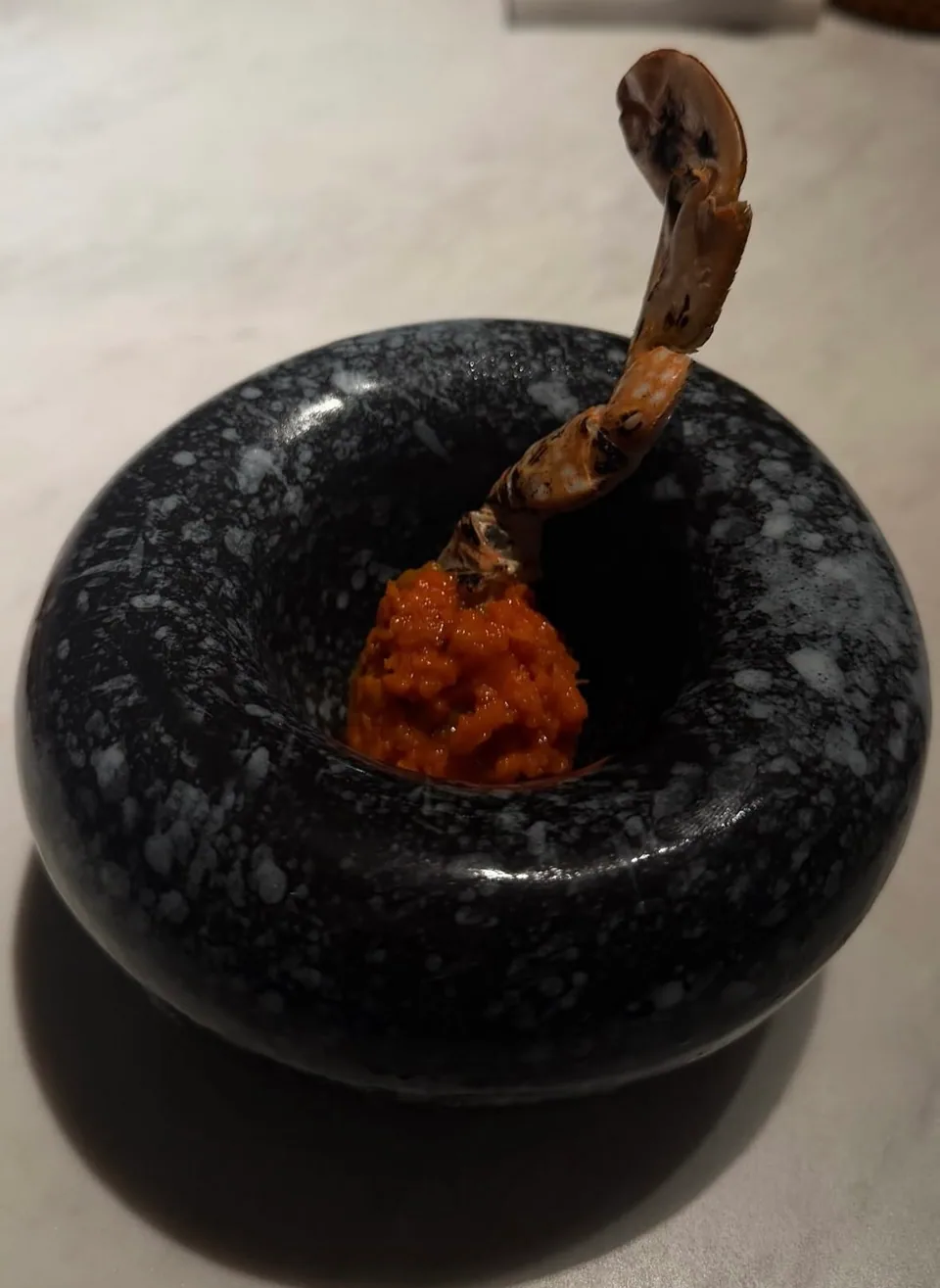 A carefully plated seafood creation in a dark ceramic bowl
