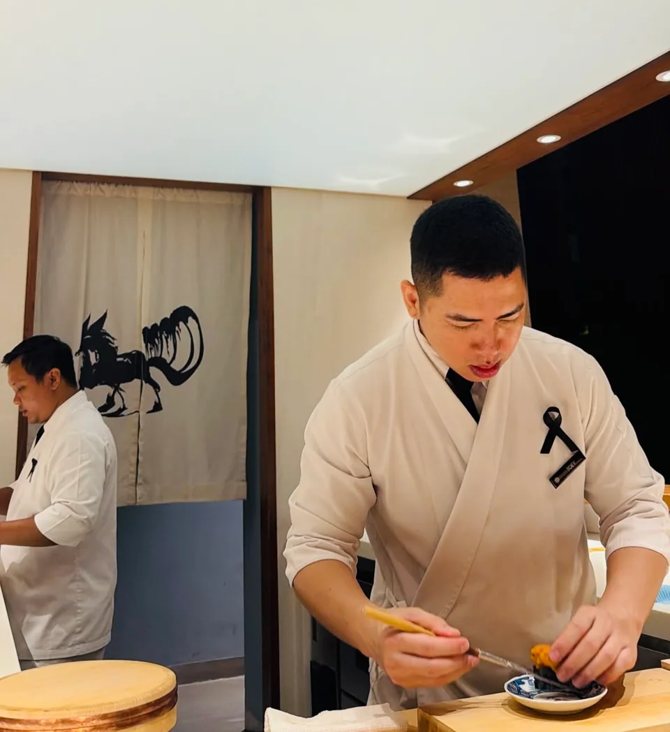 An omakase chef finishing a course at the counter