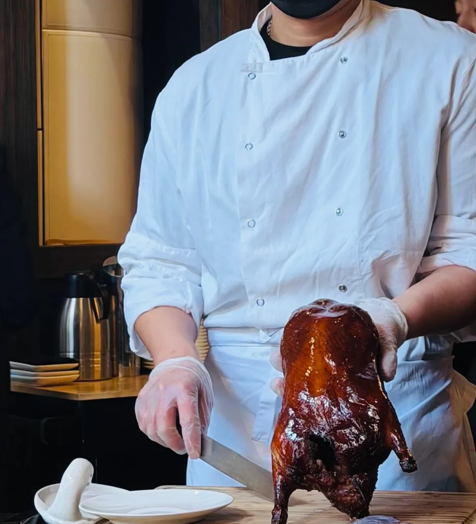 A chef carving a glossy roast duck