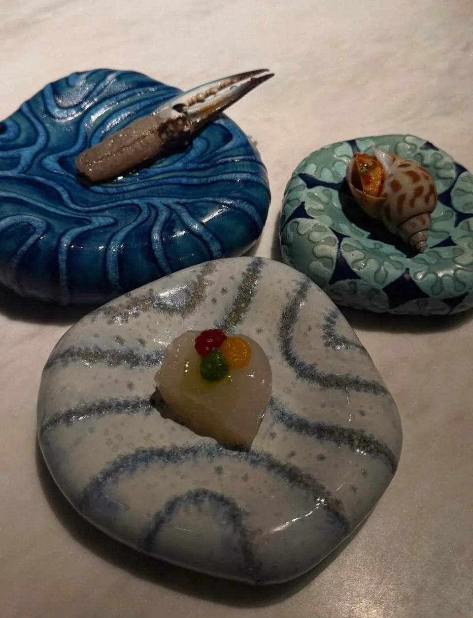 Seafood courses arranged on sculptural ceramic plates