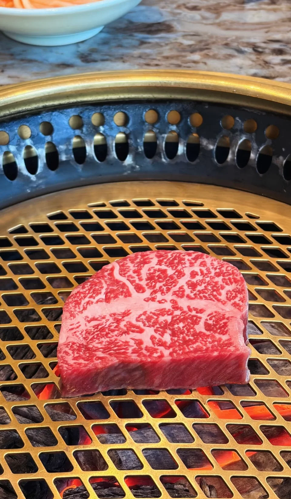 Marbled wagyu cooking over glowing coals